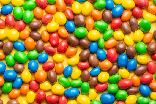 colored crunchy chocolate balls occupying the entire image on a yellow background with soft lighting