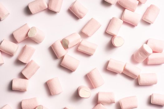 pink and white marshmallows randomly distributed on white background with soft side light