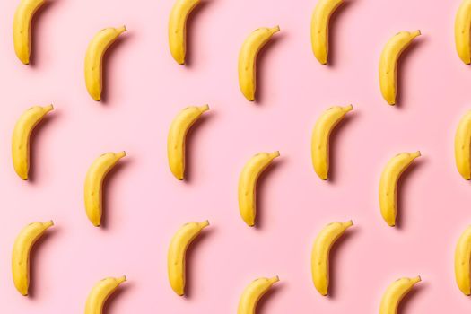 symmetrical pattern of ripe bananas on a pink background with soft side lighting