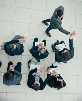 top view. happy employees giving each other a high five at a work meeting.