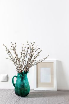 Blank canvas frame mockup. Artwork in interior design. View of modern style interior with canvas for poster on wall. Living room, table with green pitcher with willow branches. minimalism concept