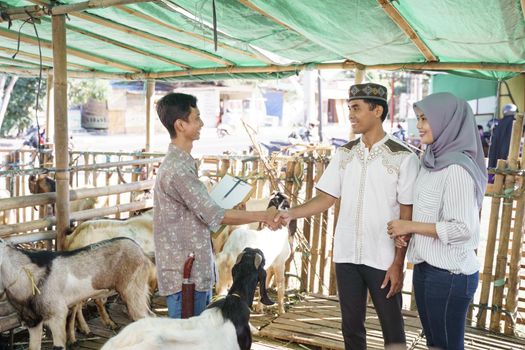 muslim people shake hand with farmer after buying a goat. idul adha sacrifice celebration