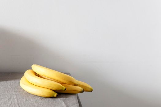 A bunch of bananas on a beige table against a white wall. Scandinavian style. Minimalism. Place for text
