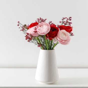 Persian pink buttercup in a beige wicker basket on a white background. Copy space