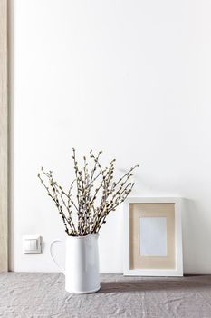 Blank canvas frame mockup. Artwork in interior design. View of modern style interior with canvas for poster on wall. Living room, table with white pitcher with willow branches. minimalism concept