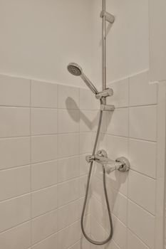 The interior of a modern bathroom made of white tiles with a metal shower