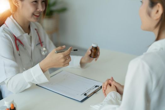 Female doctor giving pills bottle to patient in clinic. Concept of healthcare, medical treatment and insurance.