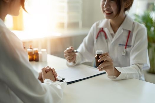 Female doctor giving pills bottle to patient in clinic. Concept of healthcare, medical treatment and insurance.