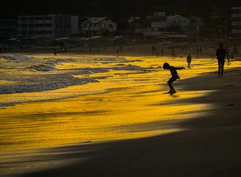 Kid playing at dusk waves. Shooting Location: Kamakura City, Kanagawa Prefecture