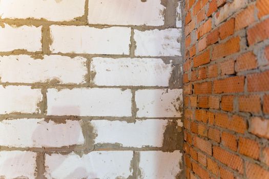 A white aerated concrete block wall joins a red brick wall