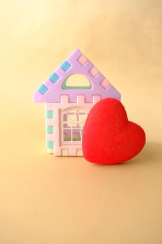 a house and heart shape symbol on color background .