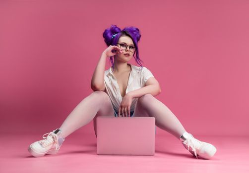 the sexy girl with glasses and purple hair with a laptop on a pink background