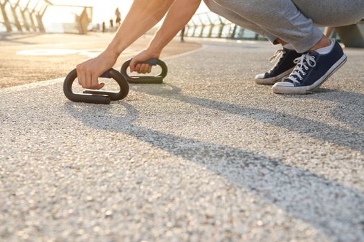 Cropped image of an athlete exercising outdoor, doing push-up exercises. Fitness, sport, endurance, body weight training, outdoor workout, healthy and active lifestyle concept. Close-up