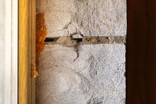 The gap between the window and the wall is filled with mounting foam, close-up. Aerated concrete block wall