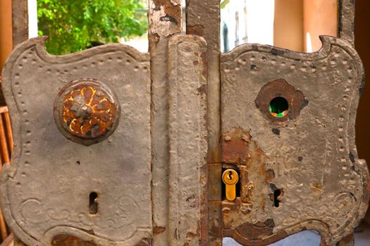 Old rusty gate with a lock in front of the house