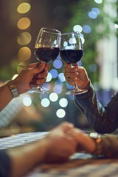 Cropped shot of a couple clinking their glasses while on a romantic date.