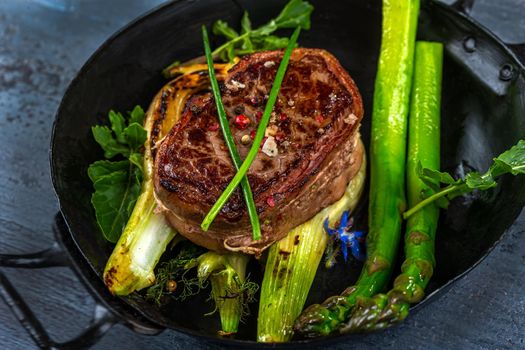 Close-up of a bleeding tournedos on a bed of green asparagus and fennel