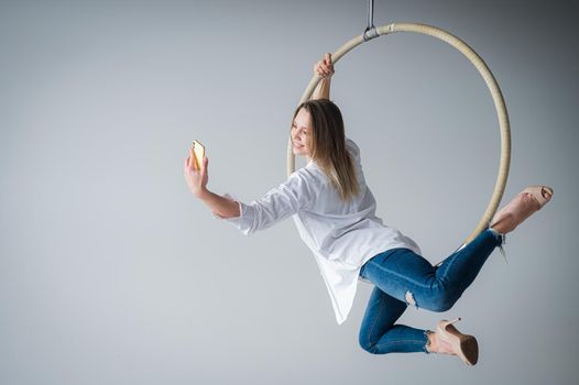 Caucasian woman gymnast on an aerial hoop takes a selfie on a smartphone