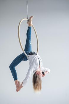 Caucasian female gymnast doing aerial hoop exercises and using smartphone