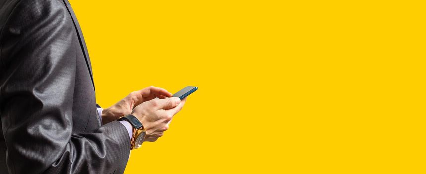 Hands of businessman calling by phone yellow background
