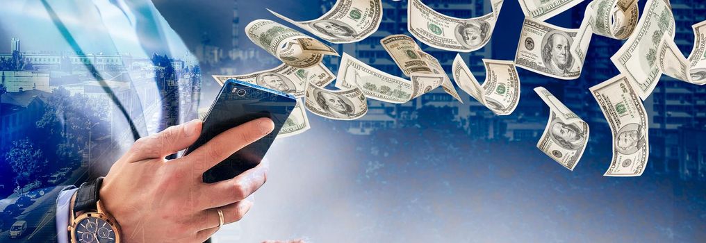 Technology online banking money transfer, e-commerce concept. Happy young man using smartphone with dollar bills flying away from screen isolated office background