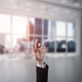 Close of businesswoman hand touching screen with finger and office at background