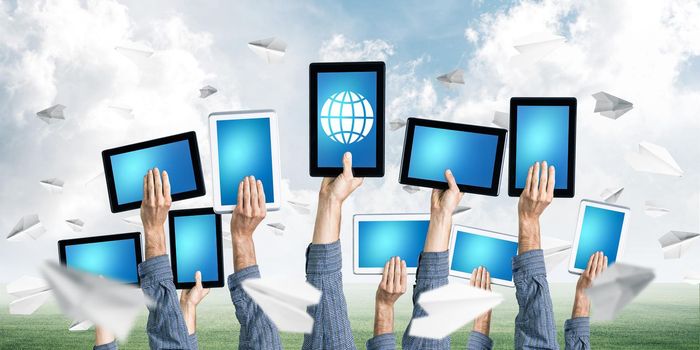 Set of tablets in male hands against nature background and paper planes in air