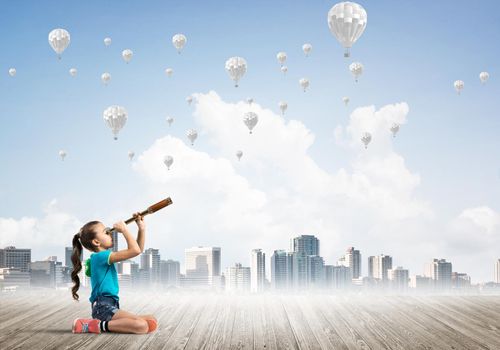 Cute kid girl sitting on wooden floor and aerostats flying in air