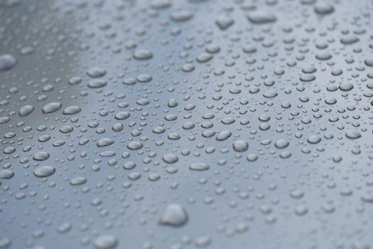 Raindrops on black hood of car. Rain on glass concept