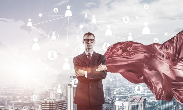 Young confident businessman wearing red cape against modern city background