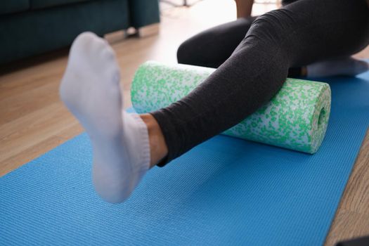 Woman massaging leg with foam roller. Body massage to relieve back pain and back muscles concept