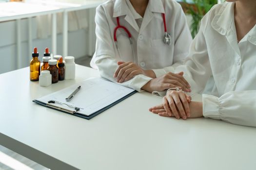 Asian female doctor in white medical uniform consult female patient in private hospital. woman therapist speak talk with woman client on consultation in clinic.