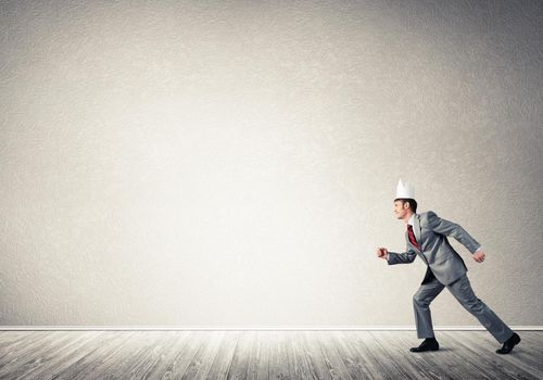 Young handsome businessman wearing white paper crown running in a hurry