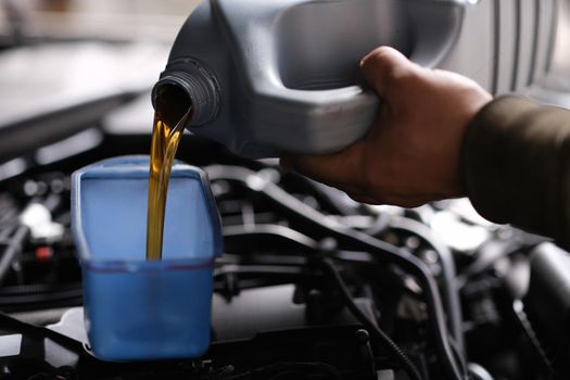 Auto mechanic pours car oil for replacement in engine. Service car in car service concept