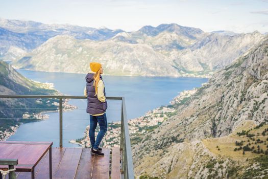 Woman tourist enjoys the view of Kotor. Montenegro. Bay of Kotor, Gulf of Kotor, Boka Kotorska and walled old city. Travel to Montenegro conceptFortifications of Kotor is on UNESCO World Heritage List since 1979.