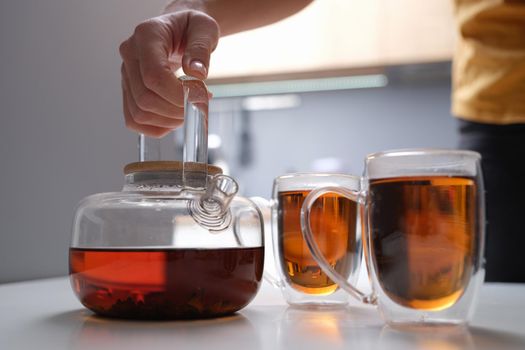 Black tea in a transparent teapot and cups. Tea brewing rules concept