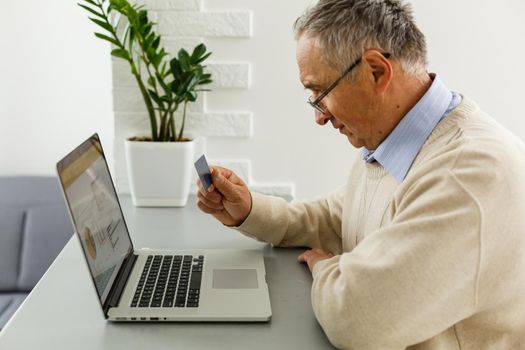 Smiling elderly senior man with laptop at home
