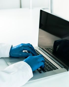 close up. doctor in protective gloves typing on a laptop . the concept of telemedicine.