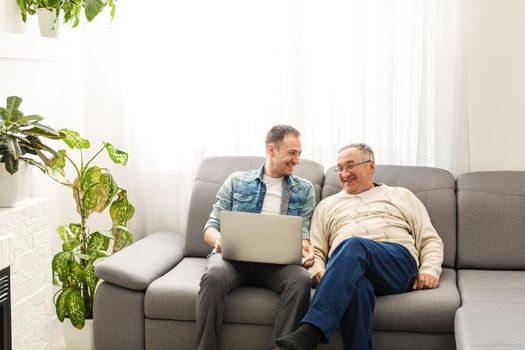 Senior man using laptop PC with his adult son