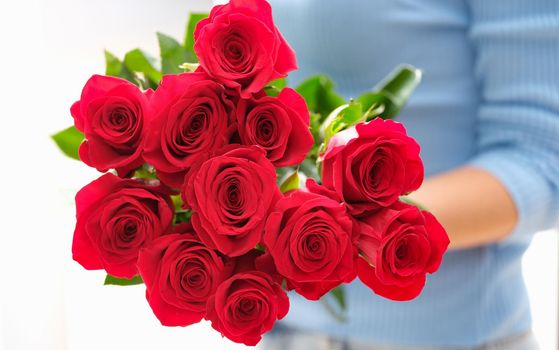 Woman is holding bouquet of beautiful red roses. Pleasant surprises for women concept
