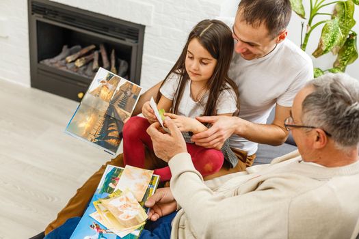 Smiling family with grandparents holding photo album at home.