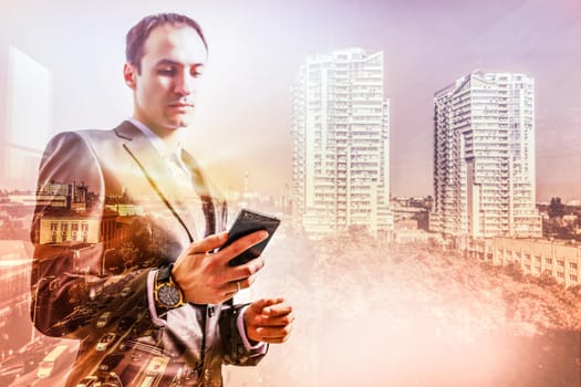 The double exposure image of the business man using a smartphone during sunrise overlay with cityscape image. The concept of modern life, business, city life and internet of things