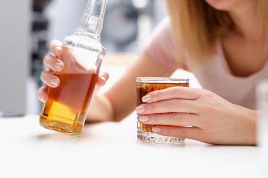 Woman with bottle of alcohol and glass alone. Depression and female alcoholism concept