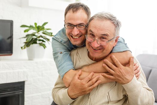 The old man on a wheelchair and his son . A man hugs his elderly father. They are happy and smiling