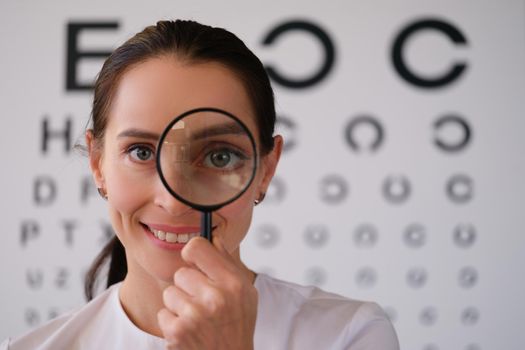 Doctor ophthalmologist looks through magnifying glass in ophthalmological clinic. Treatment of farsightedness myopia and astigmatism concept