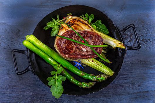 Close-up of a bleeding tournedos on a bed of green asparagus and fennel