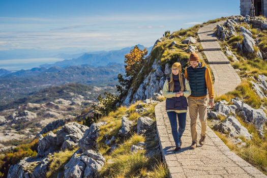 Couple man and woman tourists in mountain landscape at national park Lovcen, Montenegro. Travel to Montenegro concept.