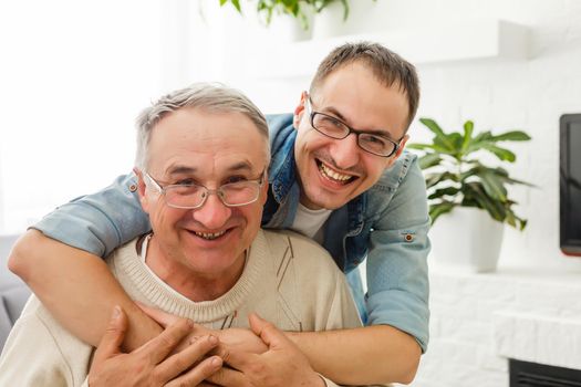 The old man on a wheelchair and his son . A man hugs his elderly father. They are happy and smiling