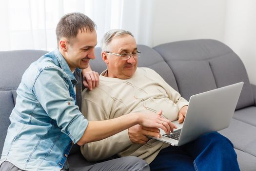 Old father and son are friendly conversation sitting at home on sofa