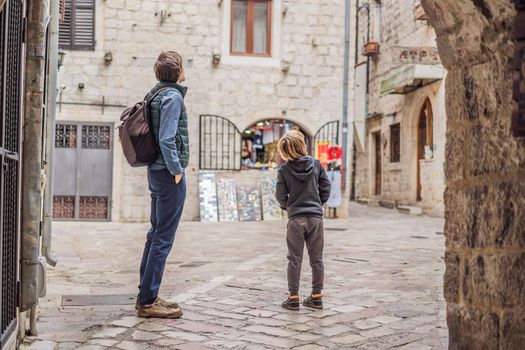Dad and son travelers enjoying Colorful street in Old town of Kotor on a sunny day, Montenegro. Travel to Montenegro concept.